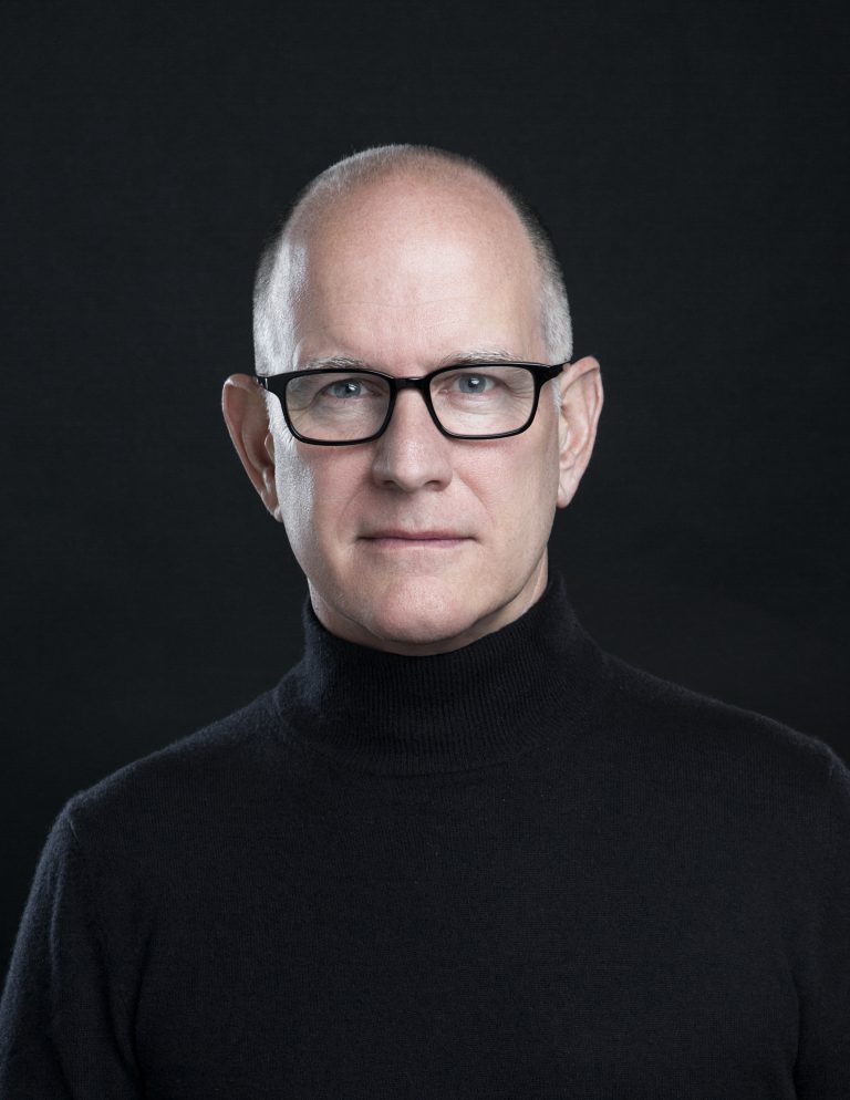 Randy Barbato wearing a black turtleneck against a dark background