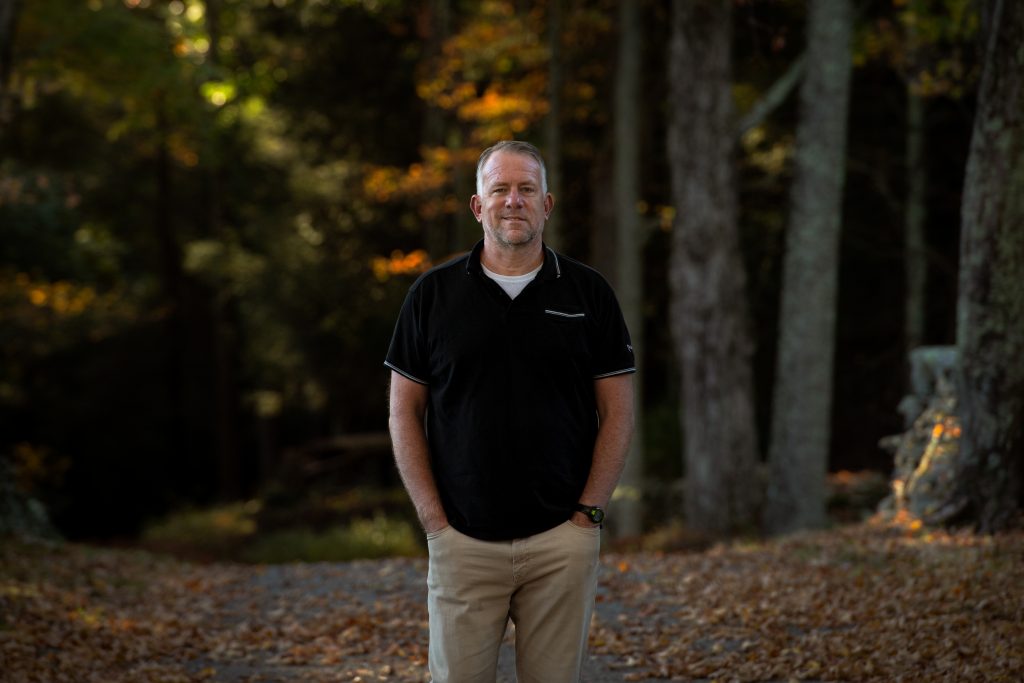 Philip Finch, MA ’97 with the woods in the background  | Photo by Derek Palmer