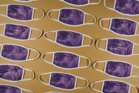 A collection of purple Emerson College face coverings on a yellow background
