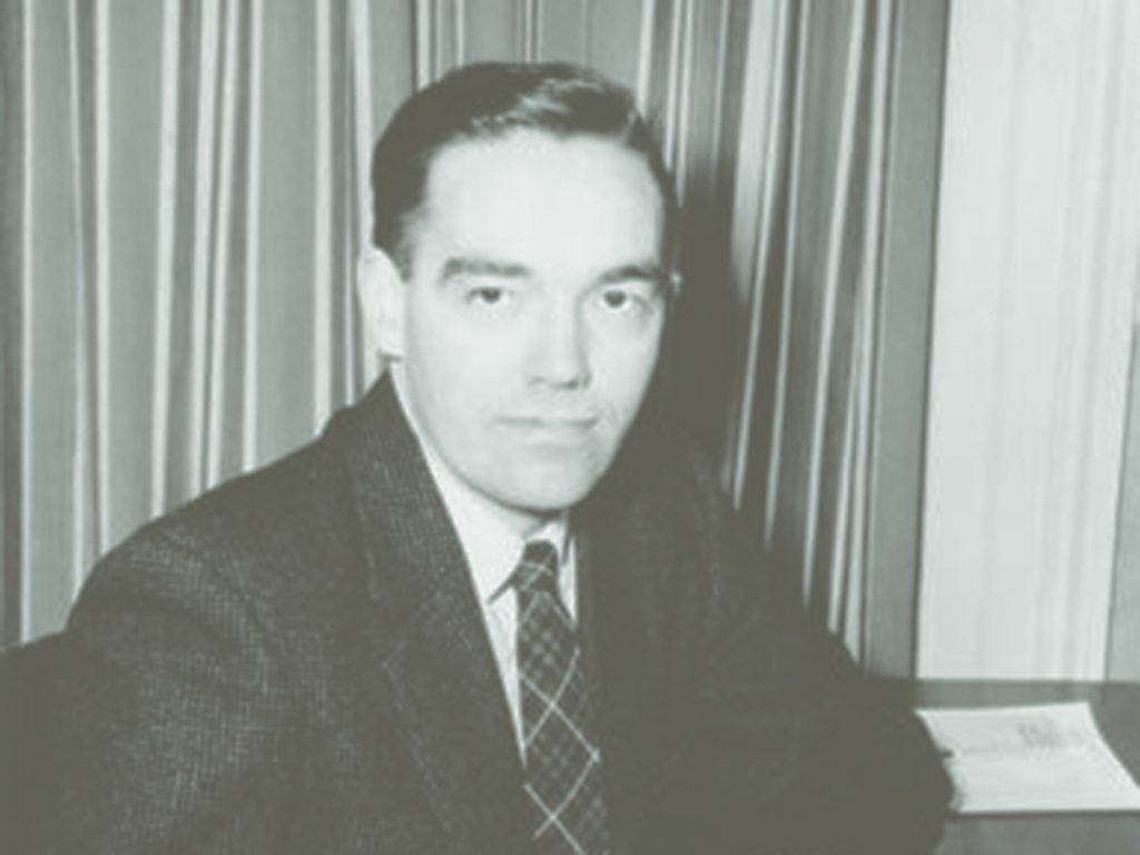 Charles Klim wearing a suit sitting at a desk