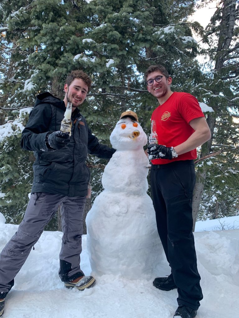 two men posing with a snowman