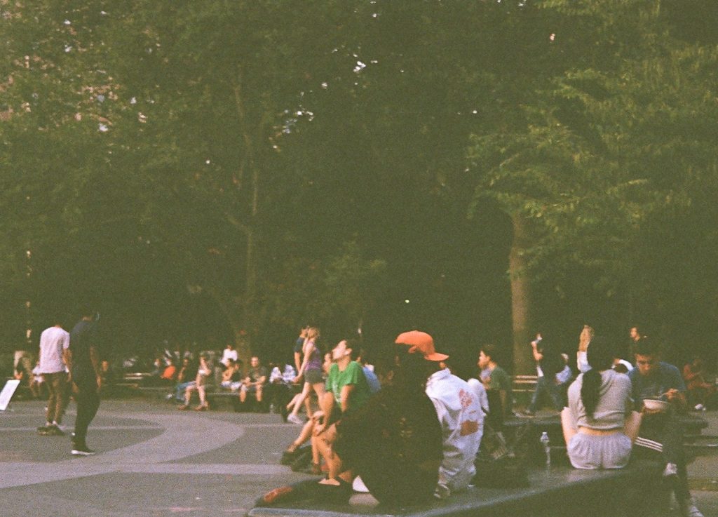 A group of people sitting outside in NYC's Washington Square Park
