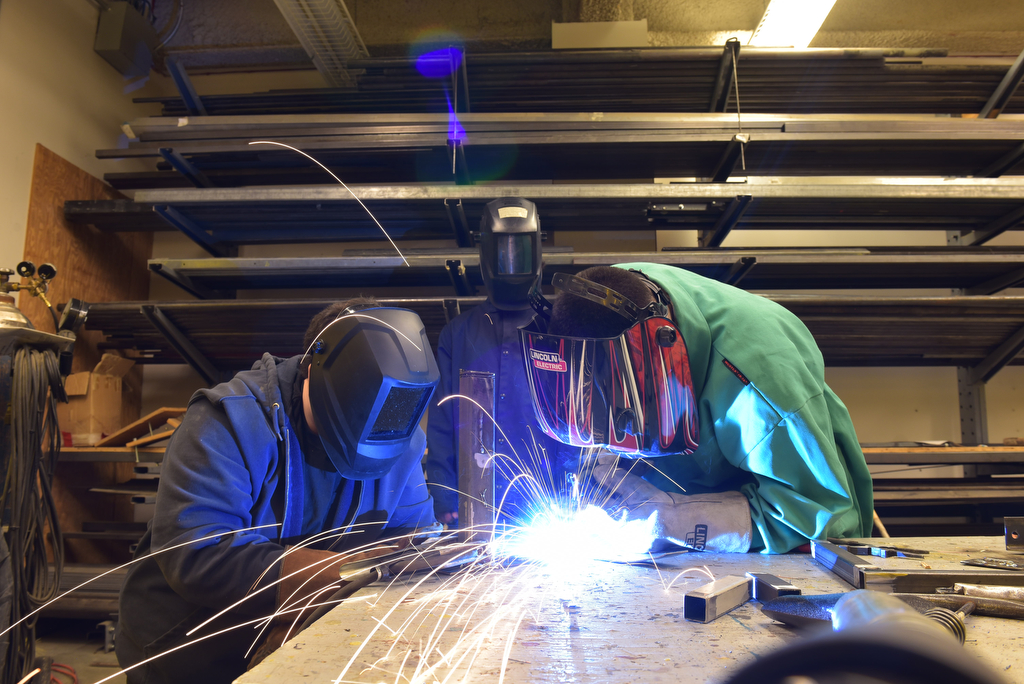 Two people welding while wearing masks