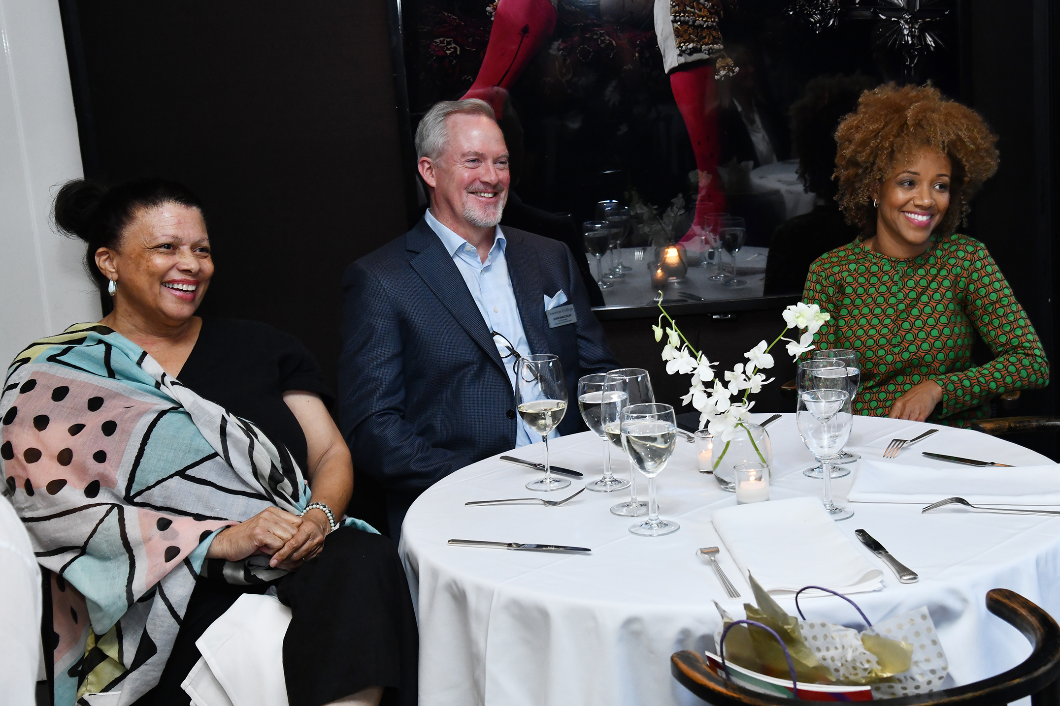 Three people sit at a table smiling