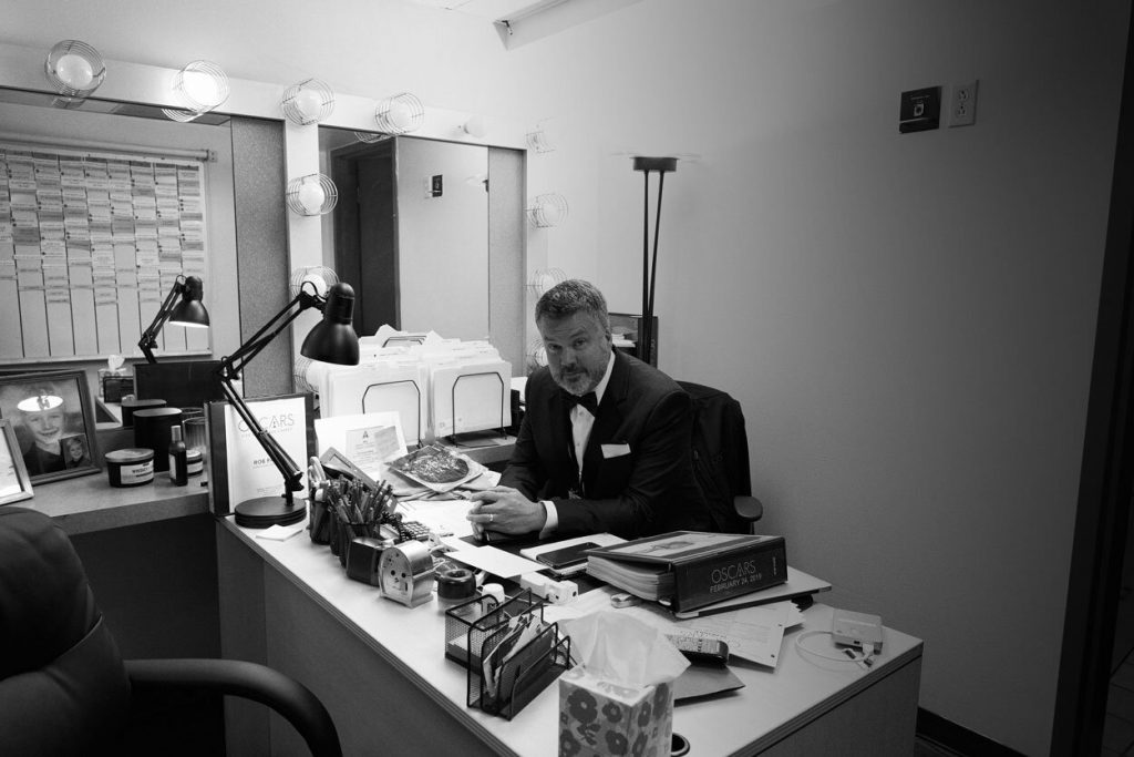 Rob Paine sits at his desk in a tuxedo