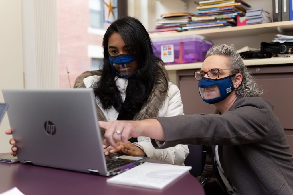 Lynn Conners points at a laptop to a student