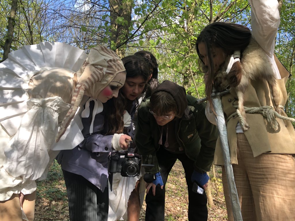 Four people look at playback on a handheld film camera