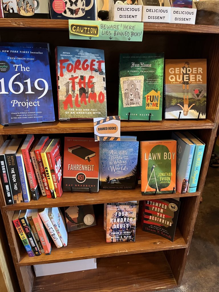 Books on a shelf at Reverie Books in Texas display New York Times bestsellers and Lambda Award winners.