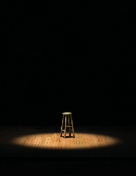 A spotlight shines on a stool in the dark