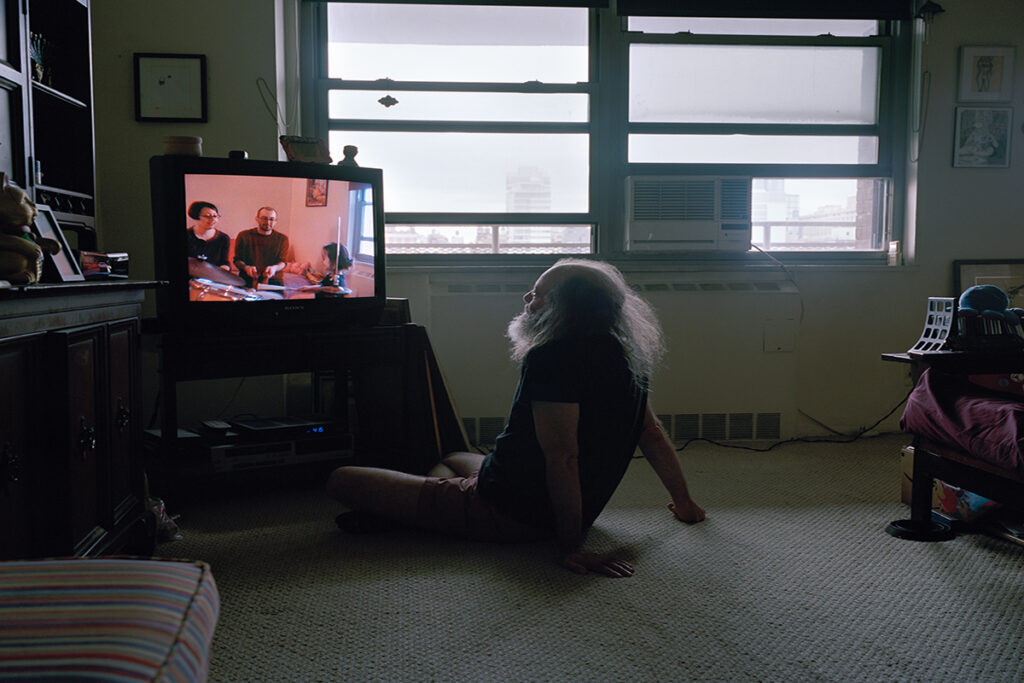 A man watches television while sitting on the floor